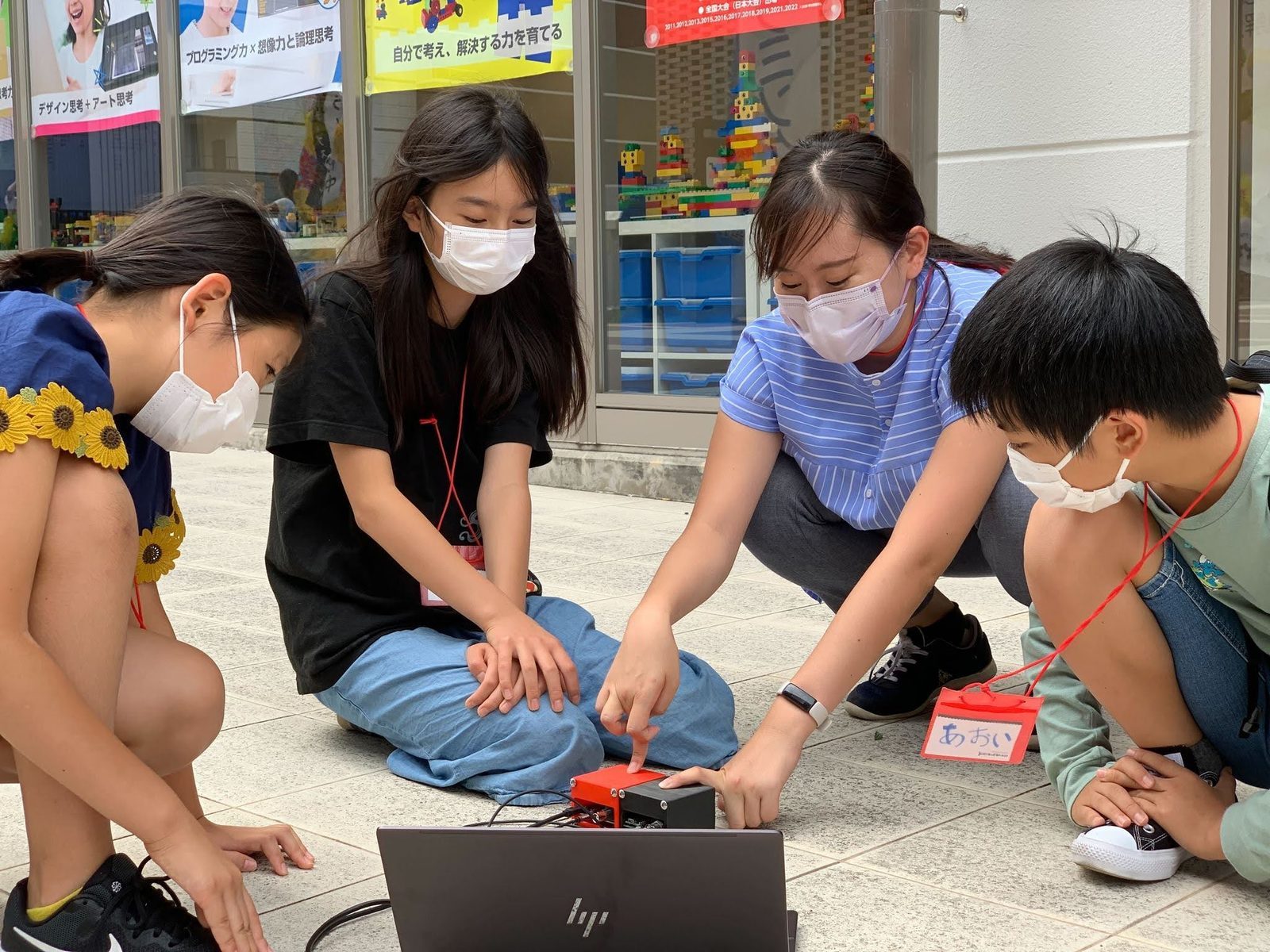 屋外でしゃがみこみ、ノートPCと検出器を見ながら測定する参加メンバーとメンター